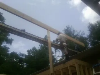Carpenter setting a ridge beam over a new addition frame — Ice Dam Removal by Roofing Brothers in Blossvale